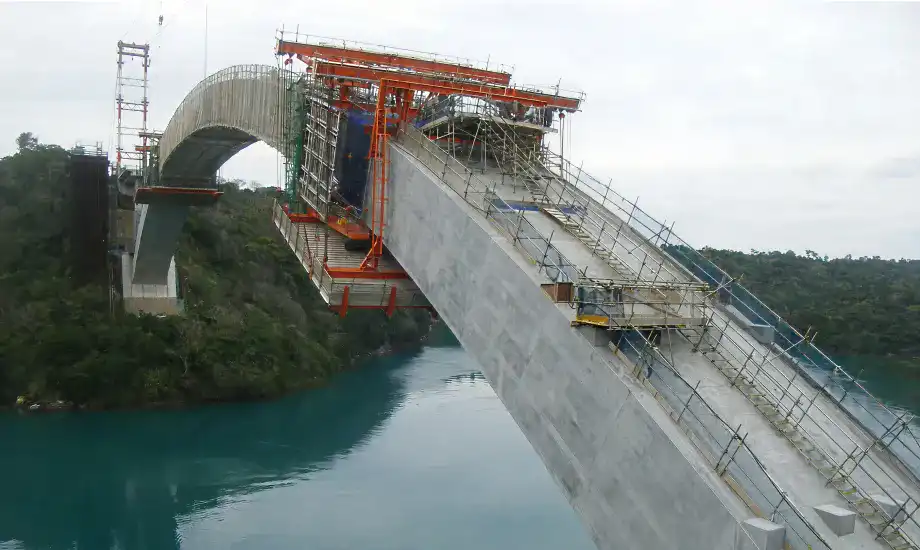 Lapping concrete construction　Using an orange form traveler,concrete is applied over the steel pipe arch.